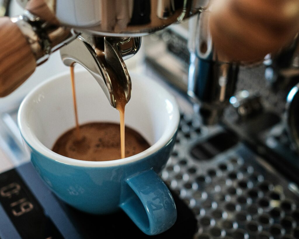 Espresso pouring from a portafilter into a blue cup