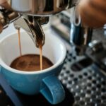 Espresso pouring from a portafilter into a blue cup