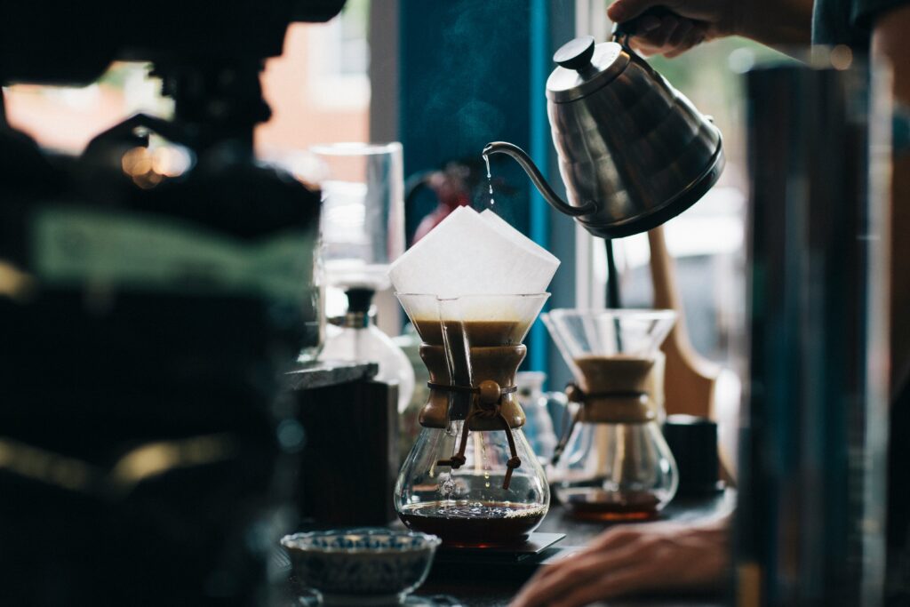 Barista pouring water from a gooseneck kettle at a pour-over bar
