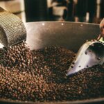 Freshly roasted coffee beans being stirred in a roaster cooling tray